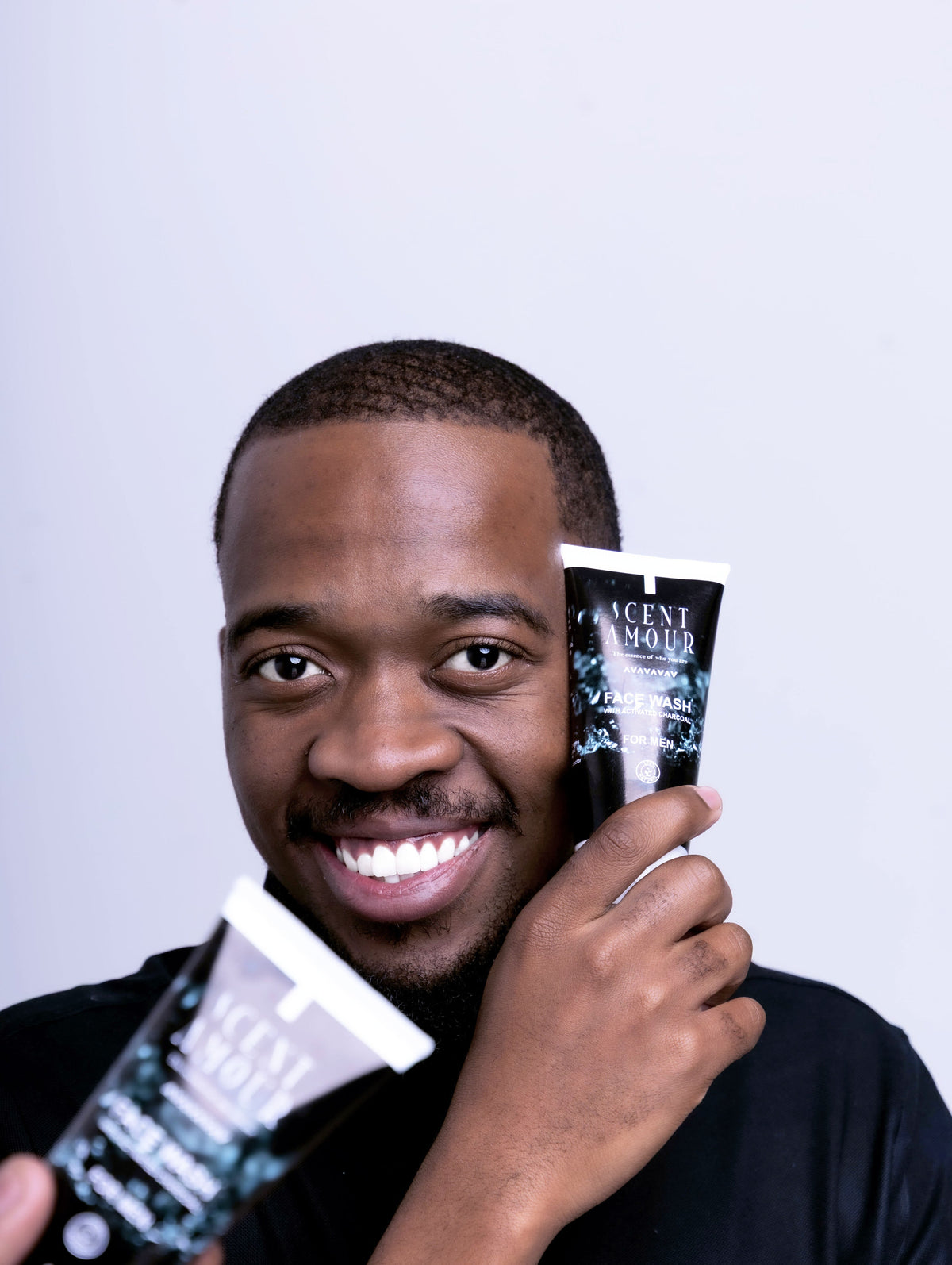 Man holding two bottles of Scent Amour face wash products against a light background