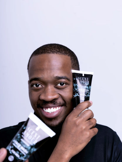 Man holding two bottles of Scent Amour face wash products against a light background