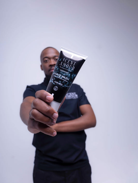 Person holding a tube of 'Scent Amour' face wash against a plain background