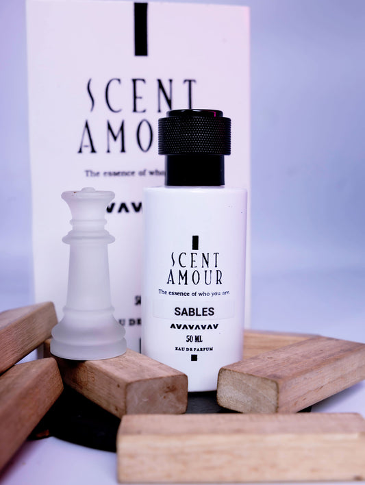 Perfume bottle and packaging with 'Scent Amour Sables' branding on a light purple background.